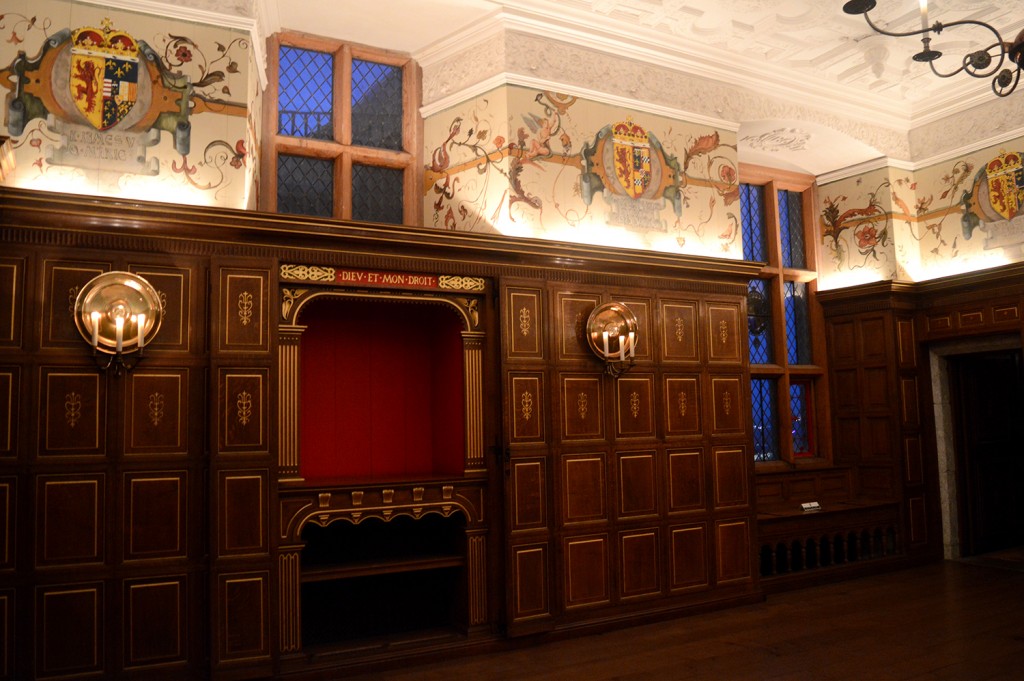 Mur à l'intérieur du château, avec blasons dessinés en haut des murs, et meubles en bois