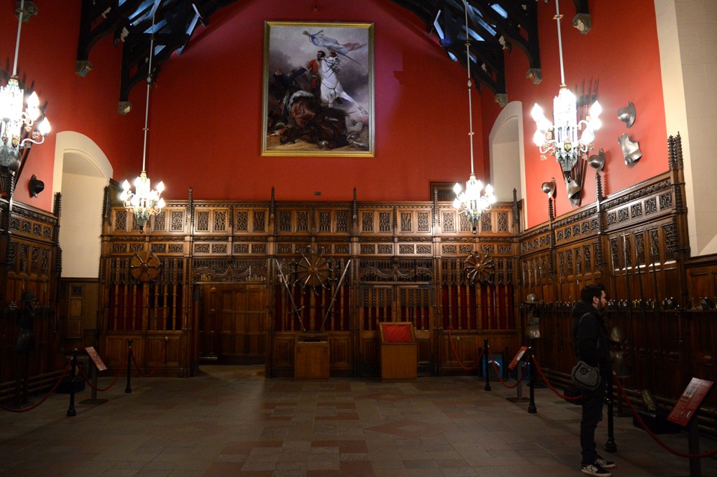 Salle à manger du château, aux murs rouges, et grands chandeliers