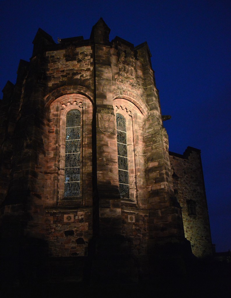 Tour du château éclairée par le bas, dans la nuit