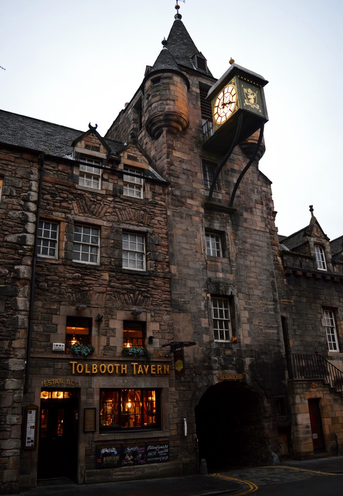 Façade en pierre d'une taverne, immeuble au toit pointu avec grande horloge suspendue