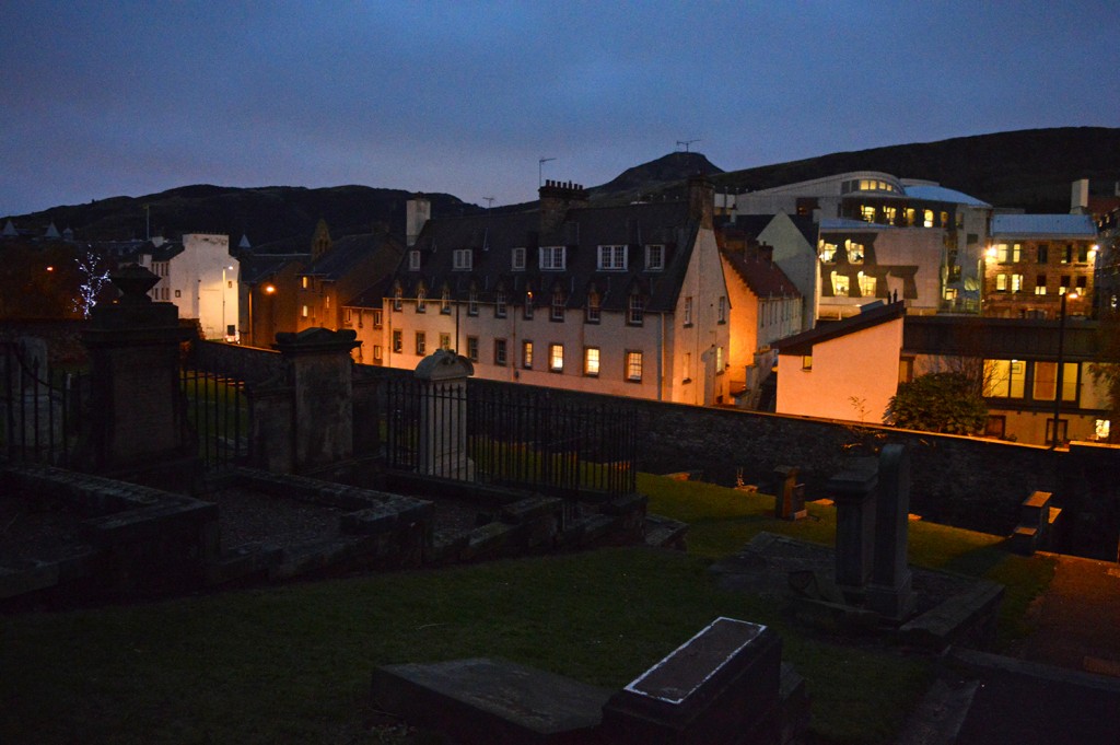 Cimetière à la tombée de la nuit, en hauteur, avec rue éclairée en contrebas