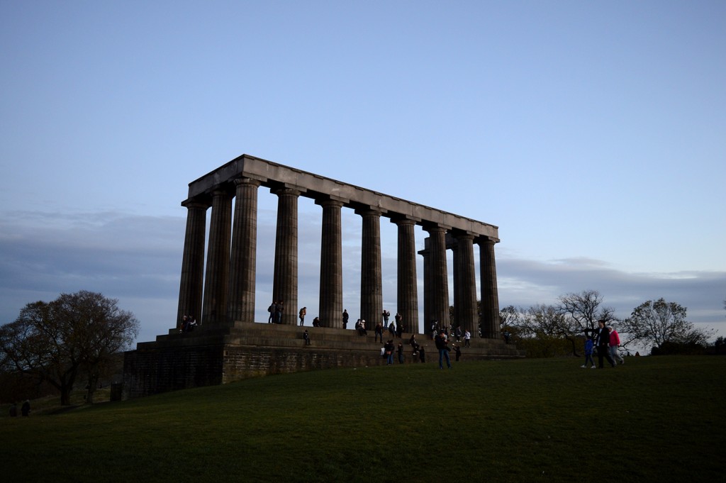 Le Monument National d'Écosse et ses 12 colonnes émergeant de l'herbe verte de la colline, au coucher de soleil