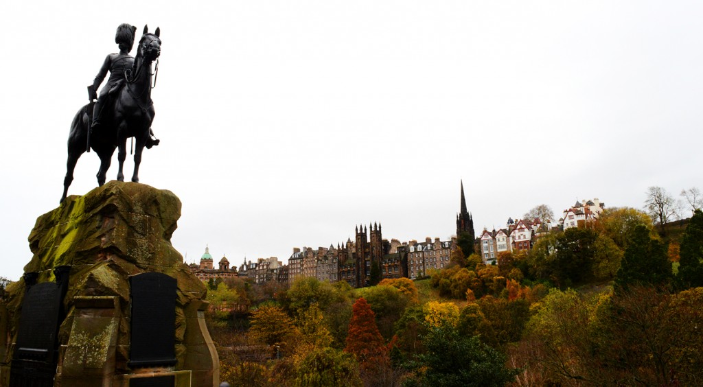 Statue d'un cavalier avec arbres rouges et jaunes au loin, et la ville au dessus sur la colline