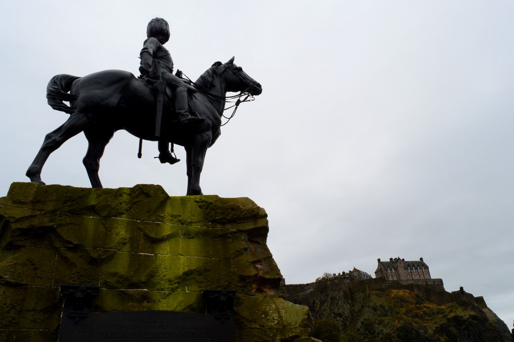 Statue d'un cavalier au premier plan, avec le château d’Édimbourg sur sa colline au loin