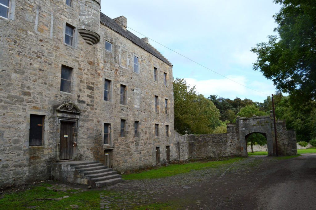 Vue sur la maison en pierre et l'entrée de la propriété, en forme d'arche