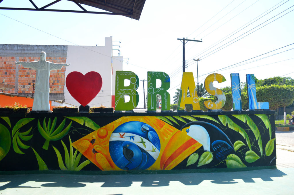 Décoration "I love Brasil", avec un christ rédempteur miniature, au dessus d'une peinture comprenant le drapeau du Brésil mélangé à des feuilles tropicales et un toucan