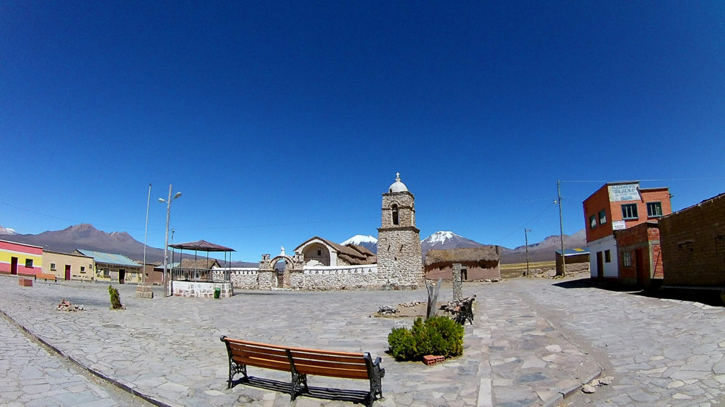 Place centrale du village de Sajama, avec un banc en premier plan, et une église en second plan