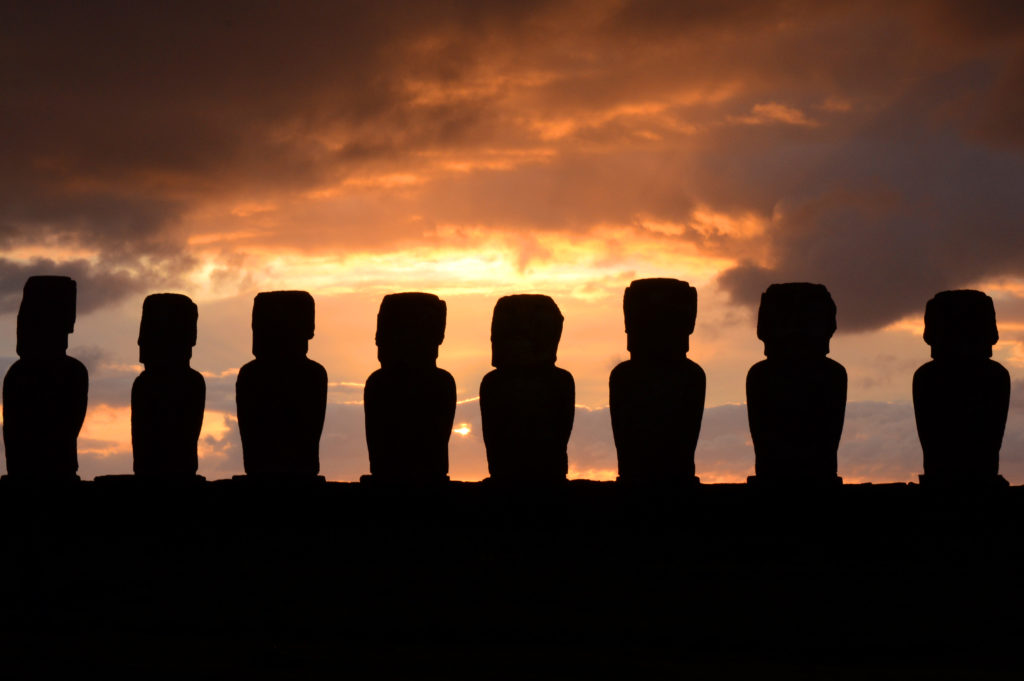 Statues en contre jour, paraissant toutes noires, devant le ciel rouge du soleil levant