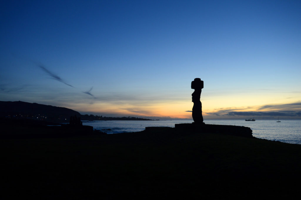 Statue de l'île de Pâques au coucher de soleil, avec l'océan derrière