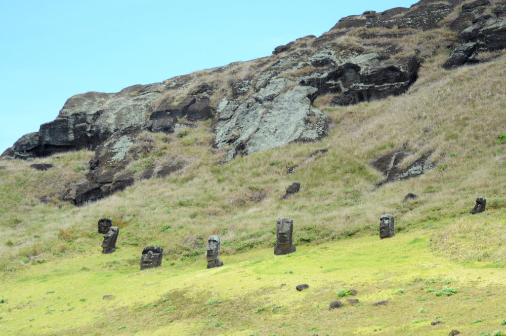 Têtes de moaïs dépassant de terre, devant la montagne