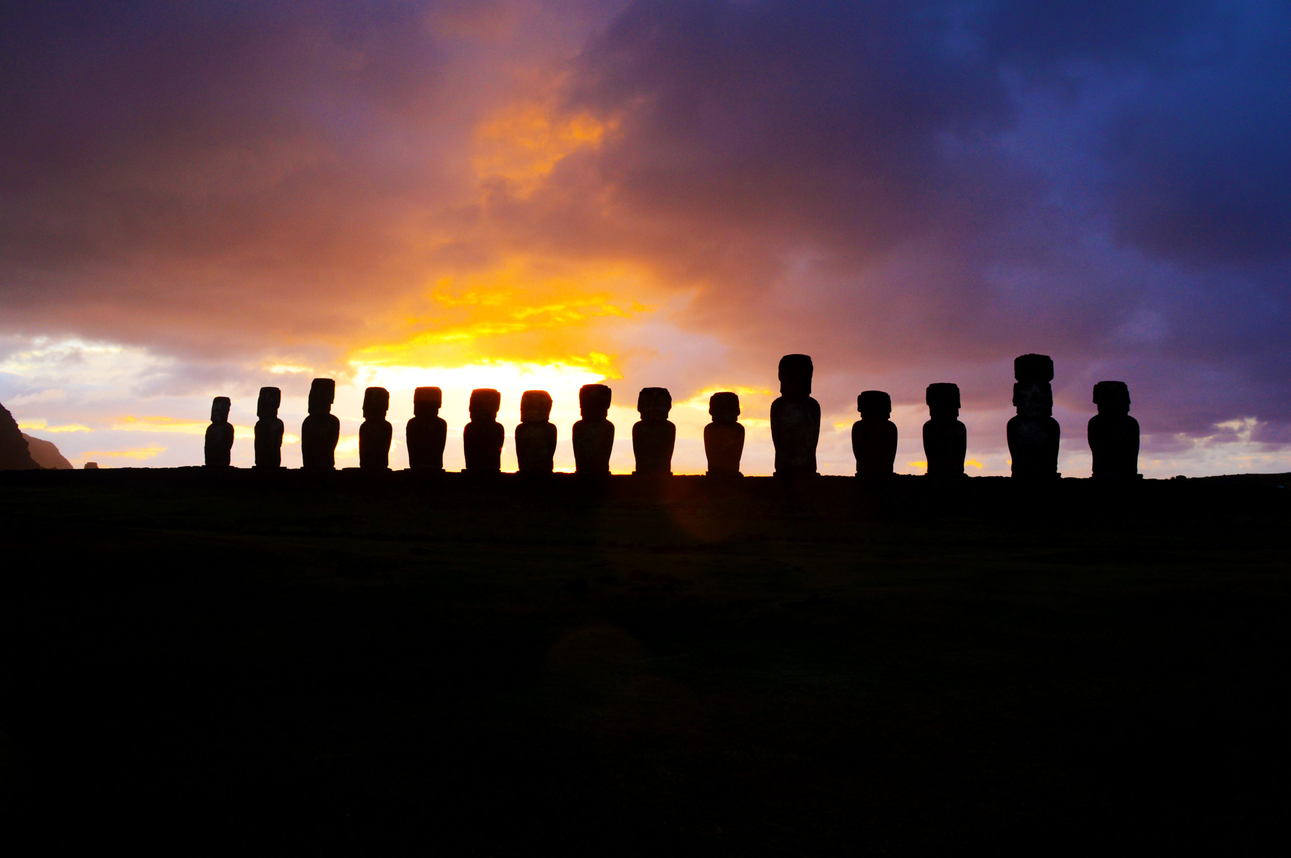 Toutes les statues de Tongariki en contre jour, paraissant toutes noires, devant le ciel rouge du soleil levant