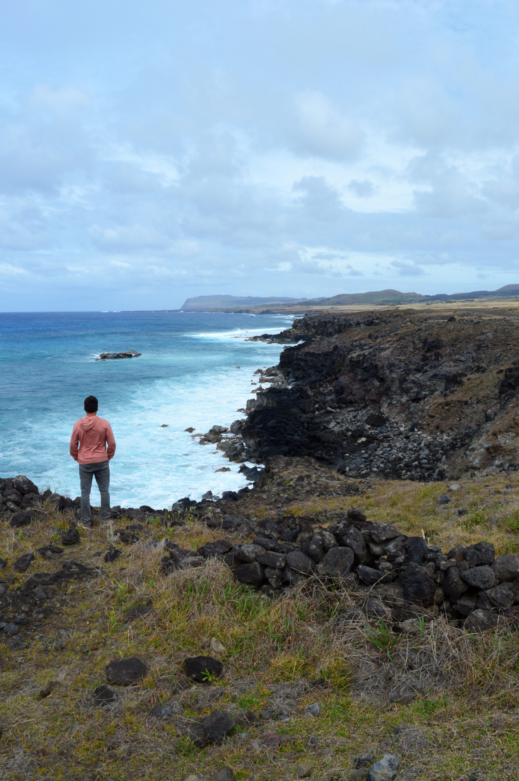 Manu admirant l'eau turquoise contrastant avec les falaises noires de l'île de Pâques