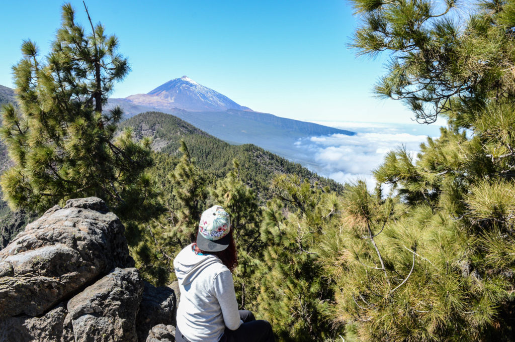 Amandine, sur un point de vue en hauteur dans le forêt, observant le volcan au loin