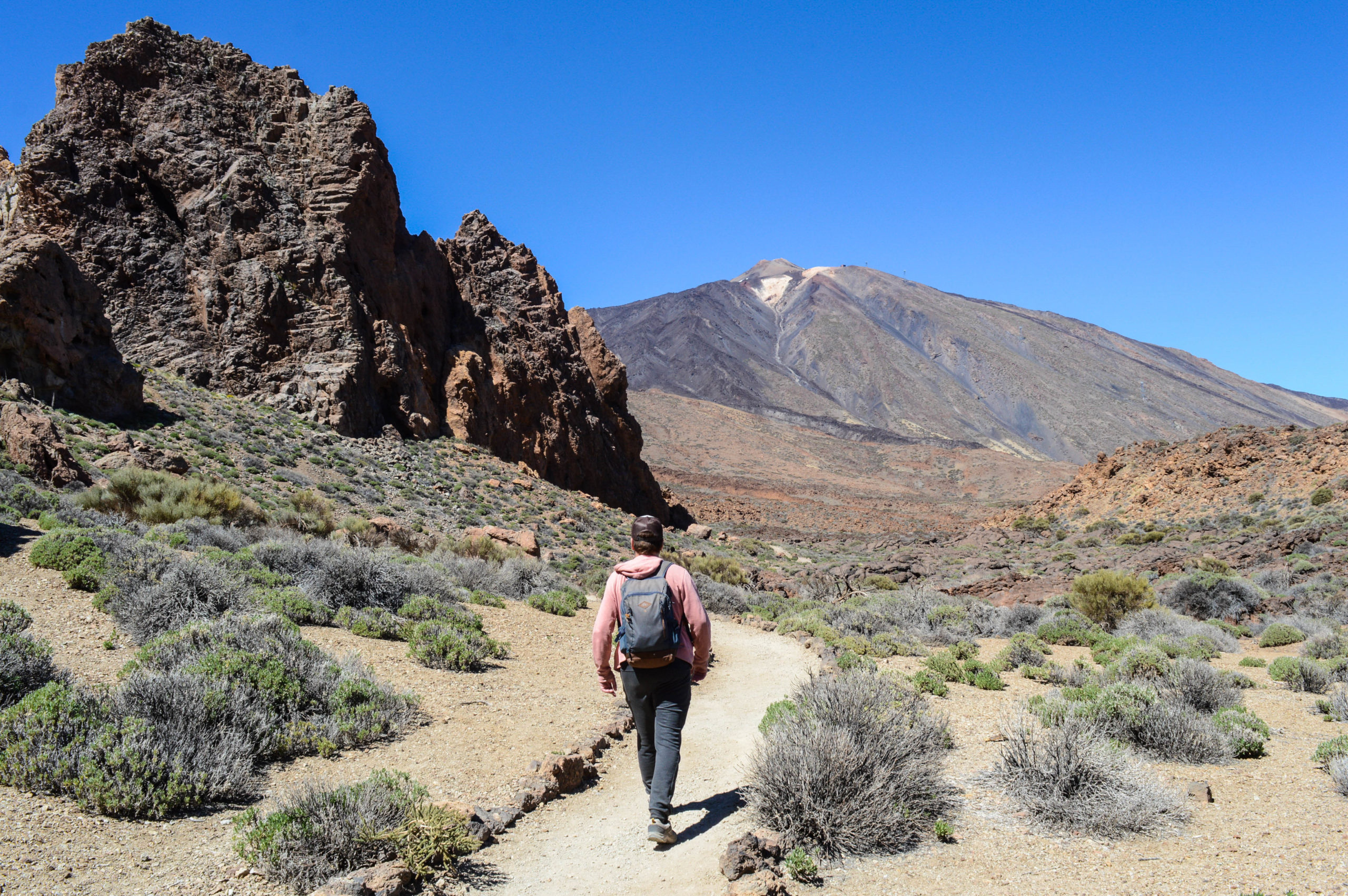 Manu marchant sur le chemin de randonnée, avec le volcan en arrière plan