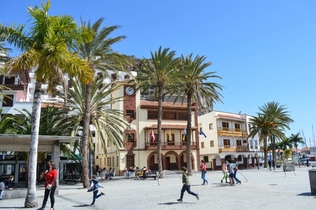 Personnes marchant sur la place principale de San Sebastian de la gomera, bordée de palmiers