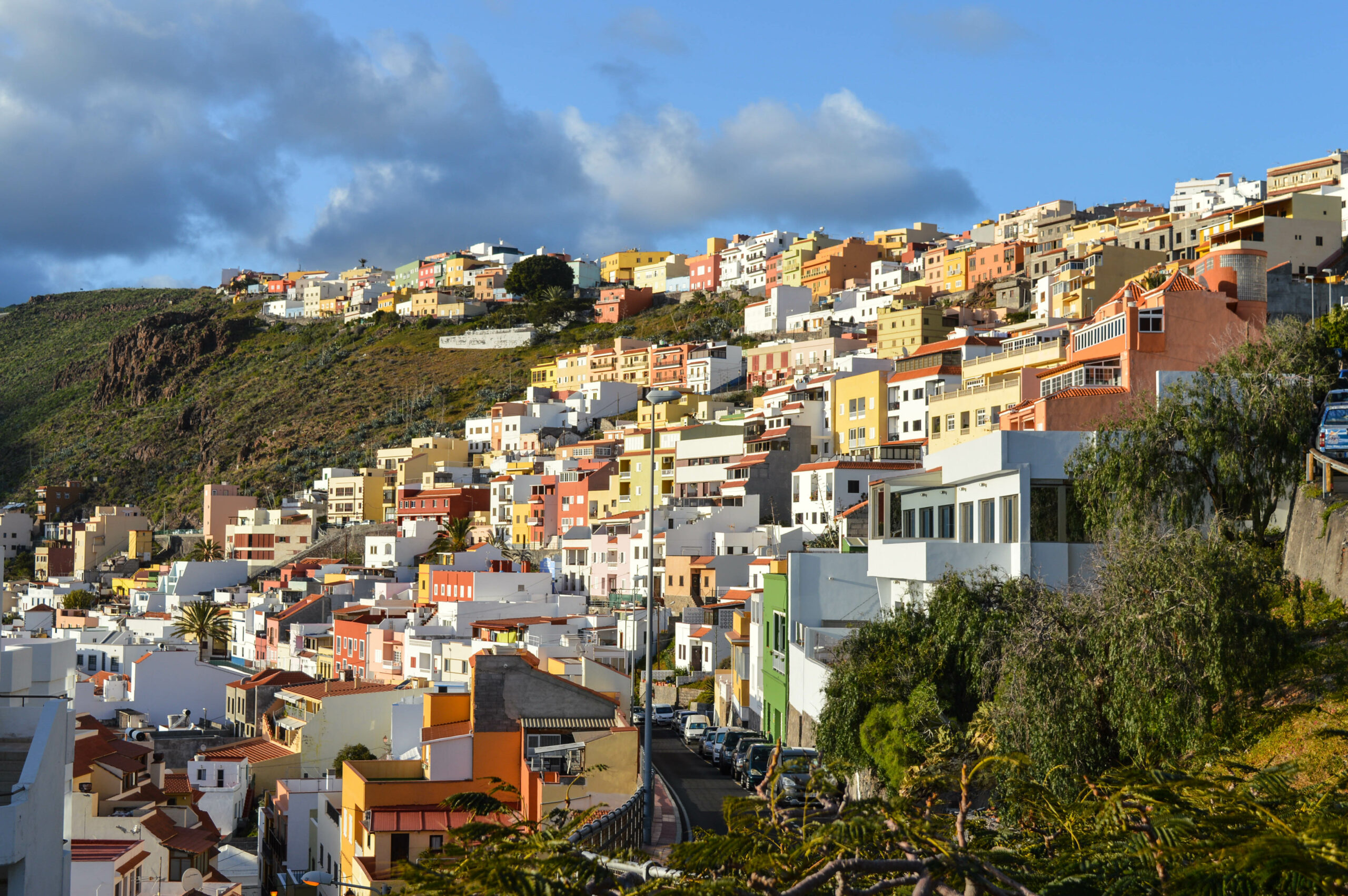 Maisons au multiples couleurs, orange/jaunes/rouge/blanches, grimpant sur la montagne verte entourant San Sebastian de la Gomera
