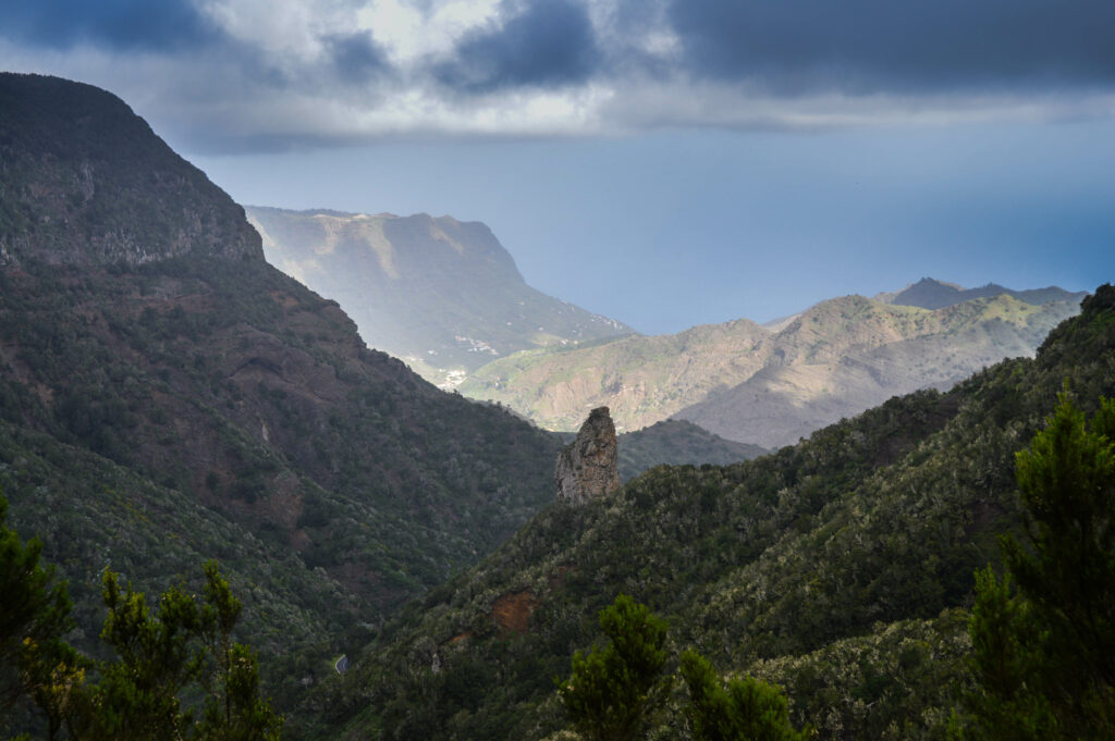 Vue sur les falaises et la vallée du parc Garajonay, sombre au 1er plan, mais avec la lumière éclairant l'arrière plan