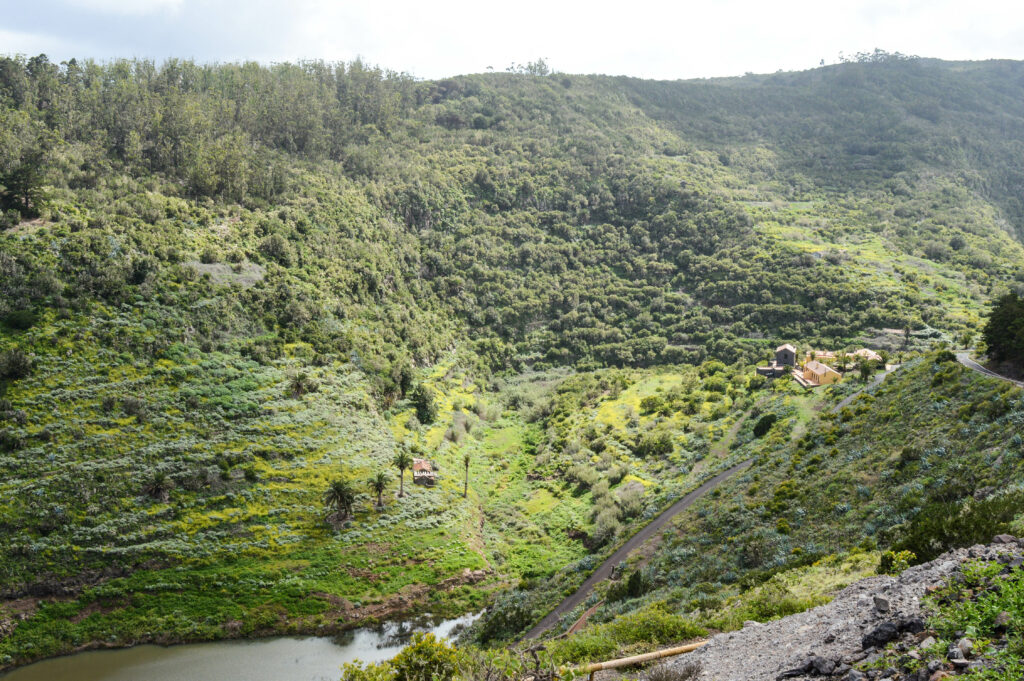 Montagne et vallée verdoyante, avec une petite maison en contrebas, et une route serpentant au milieu de la vallée