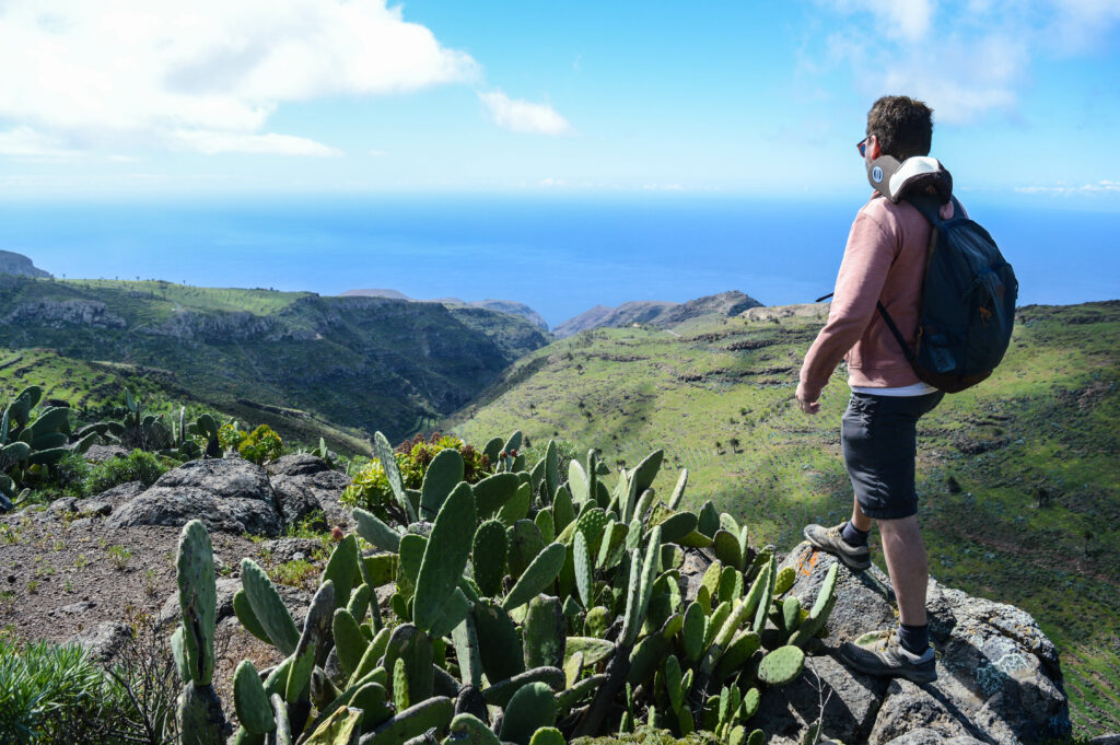 Manu debout sur un rocher, avec un cactus à sa gauche, observant la vue sur La Gomera