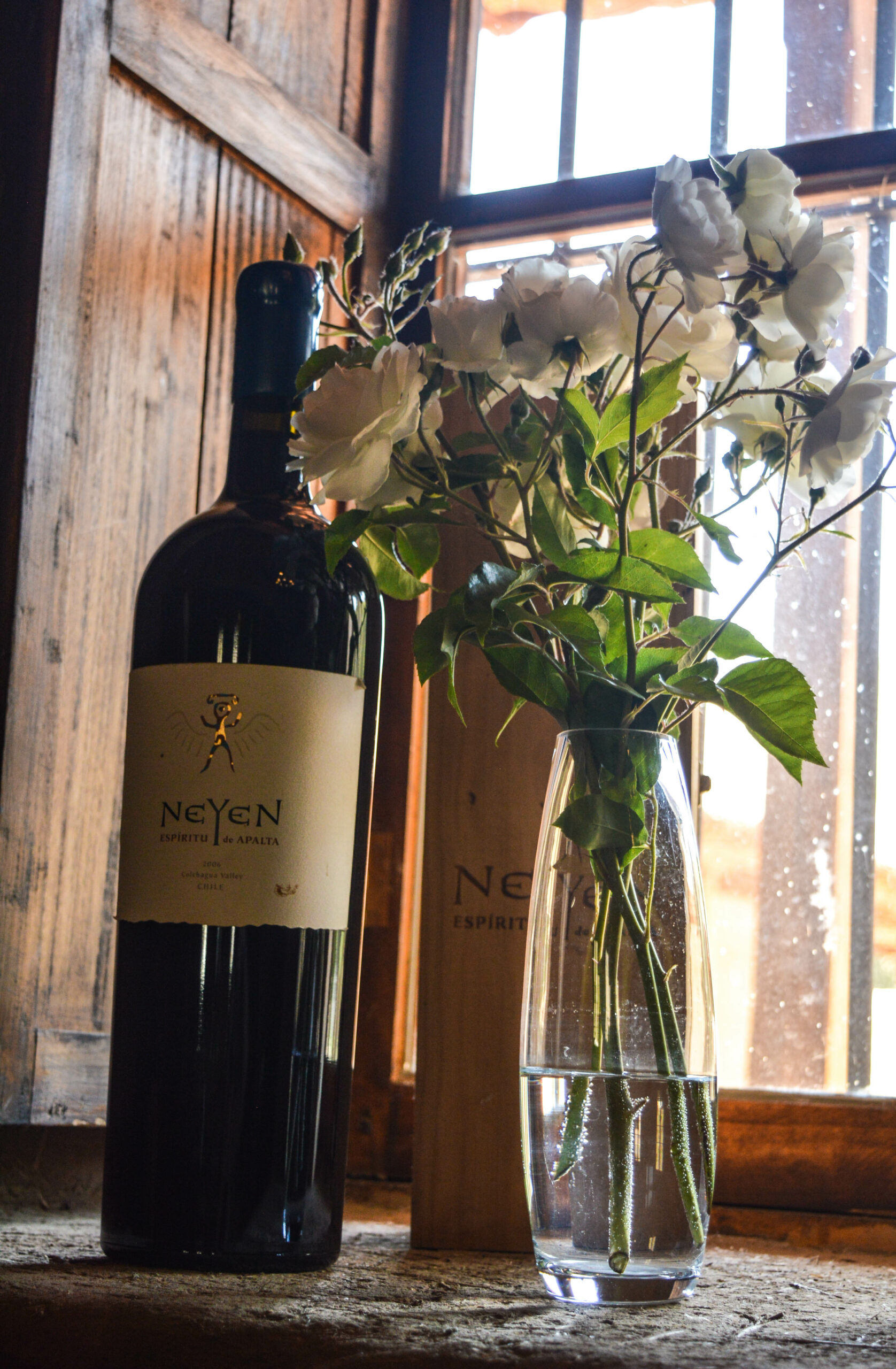 Bouteille de vin rouge Neyen à côté d'un vase avec des fleurs blanches