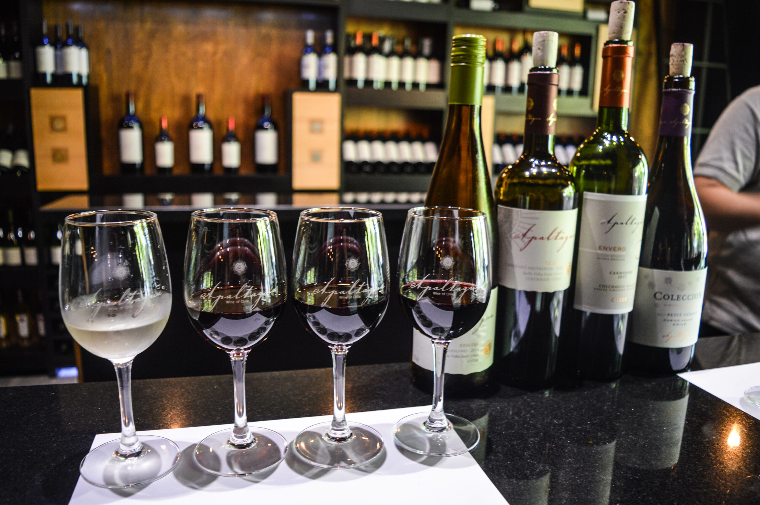 4 verres de vin sur un bar, à côté de leurs bouteilles respectives