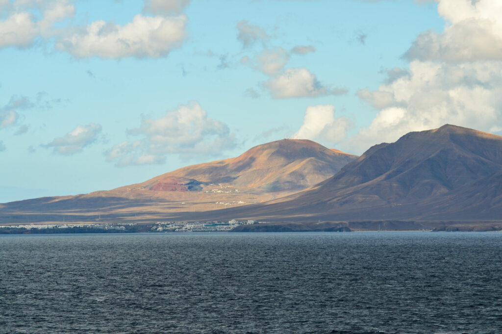 Vue sur une île éclairée avec une petite ville visible et l'océan en premier plan