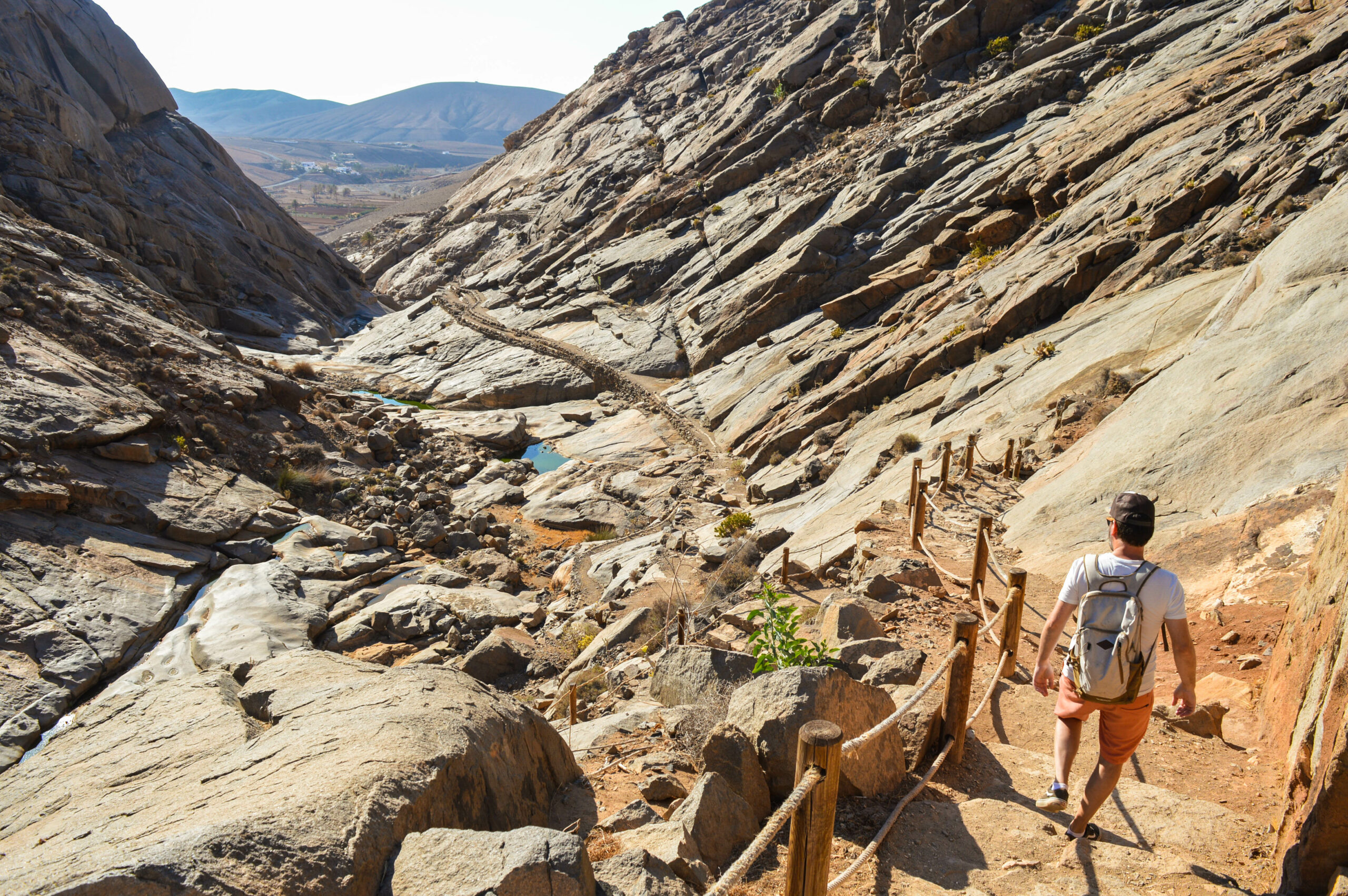 manu descend des escaliers dans un paysage rocheux en randonnée à fuerteventura