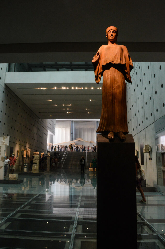 Statue d'un homme éclairée par une lumière orange dans un couloir du musée