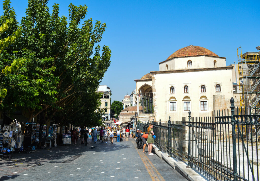 Rue pavée avec un grand arbre, et la mosquée Tzitarakis en fond