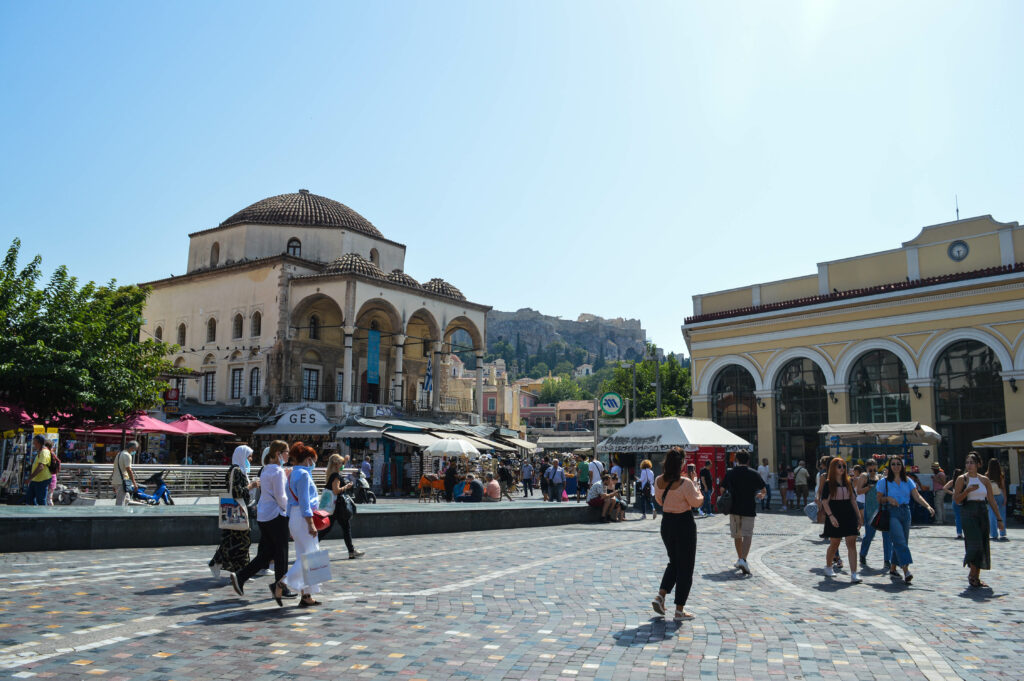 Personnes se baladant sur les pavés de la place Monastiráki, avec la mosquée Tzitarakis au fond