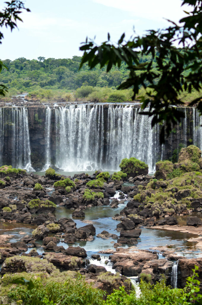 Bassin d'eau avec gros rochers, devant des chutes en arrière plan