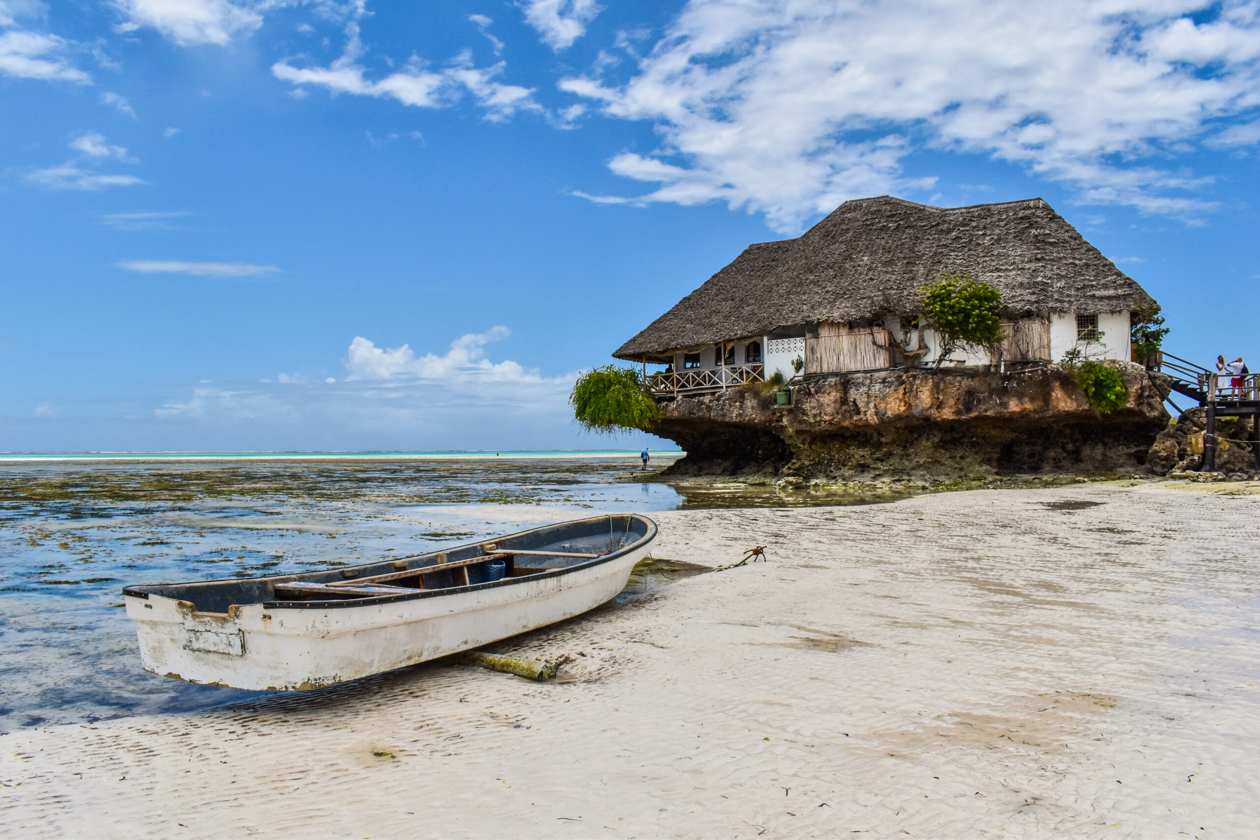 Canot sur la plage à Zanzibar, devant un restaurant installé sur un monticule rocheux