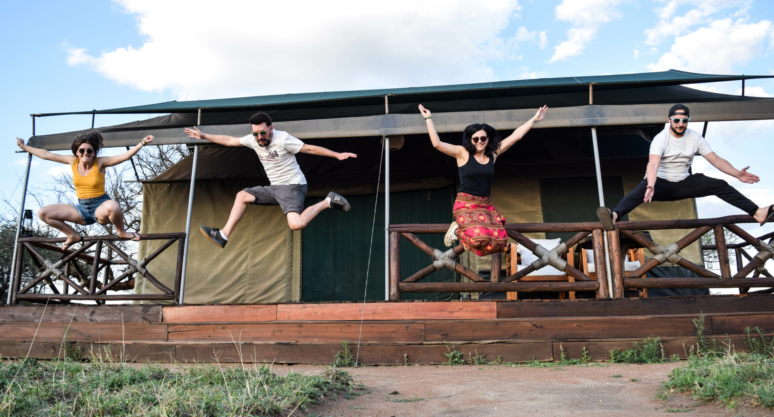 4 personnes en l'air, les bras écartés, en train de sauter depuis des marches d'un lodge dans le Serengeti