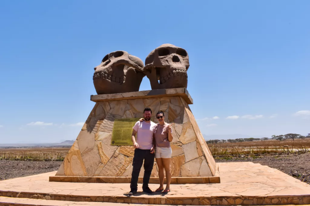 Manu et amandine devant un monument représentant 2 crânes préhistoriques