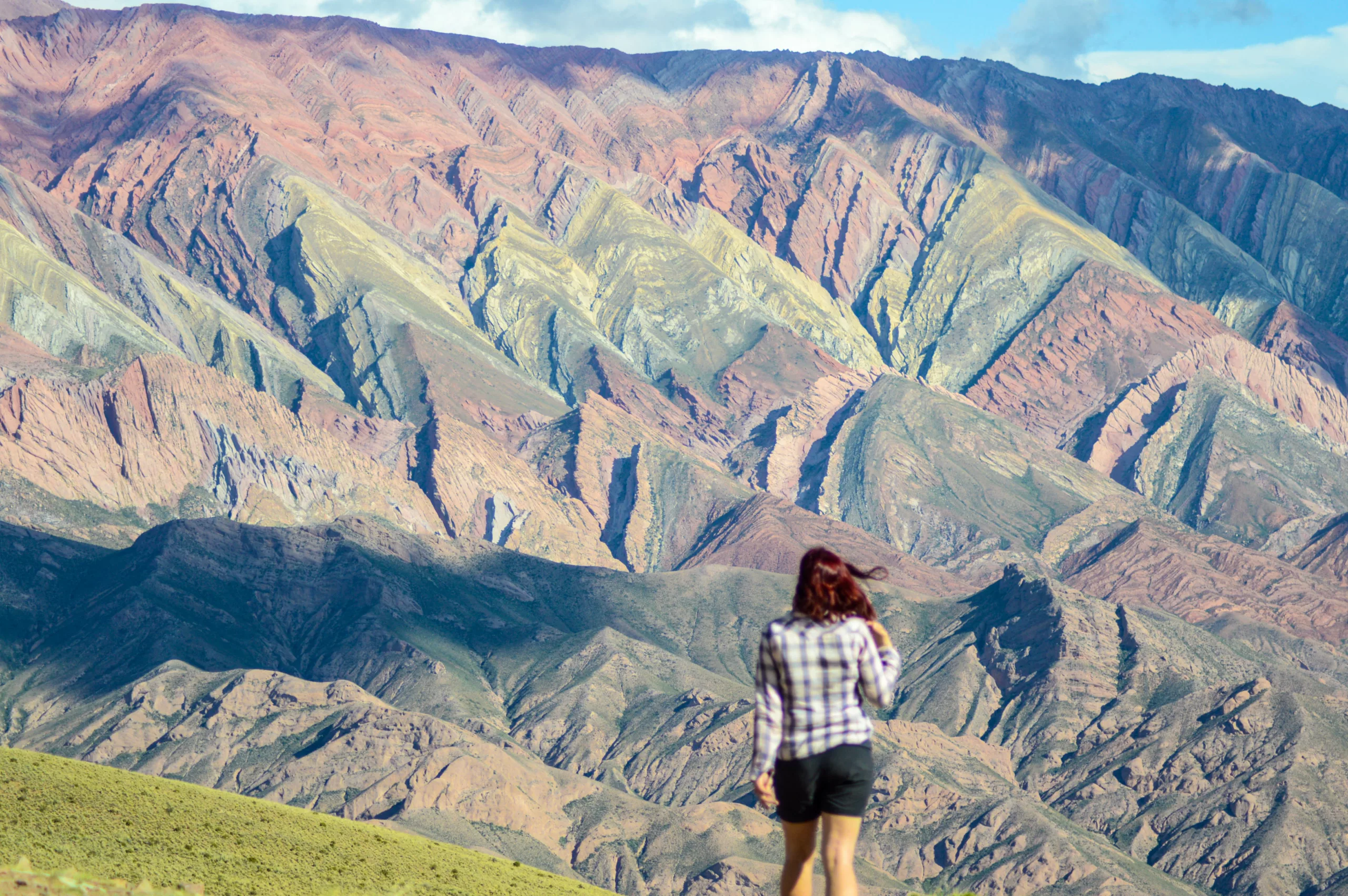 femme de dos devant montagnes colorées