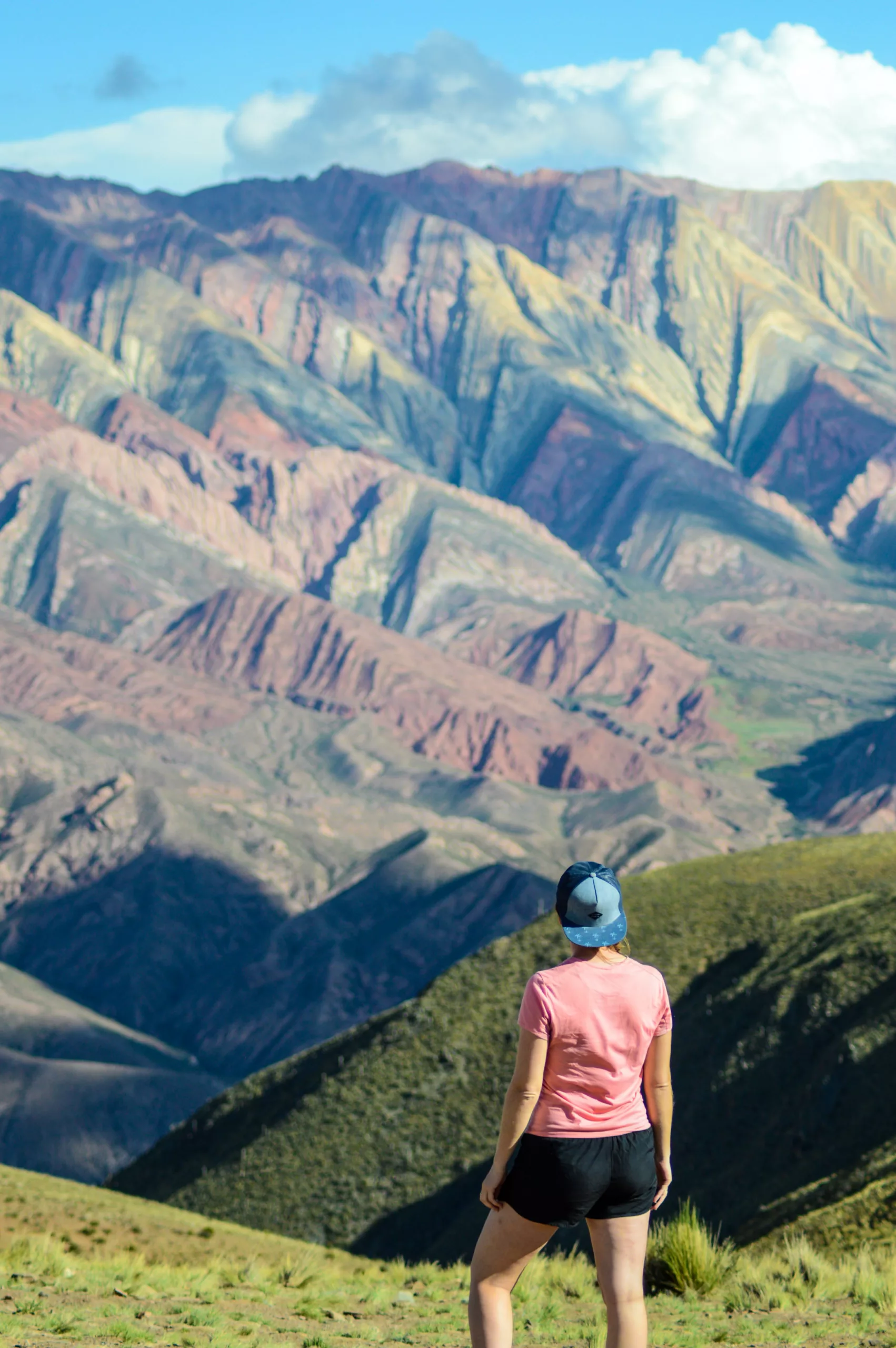 femme de dos devant montagnes colorées