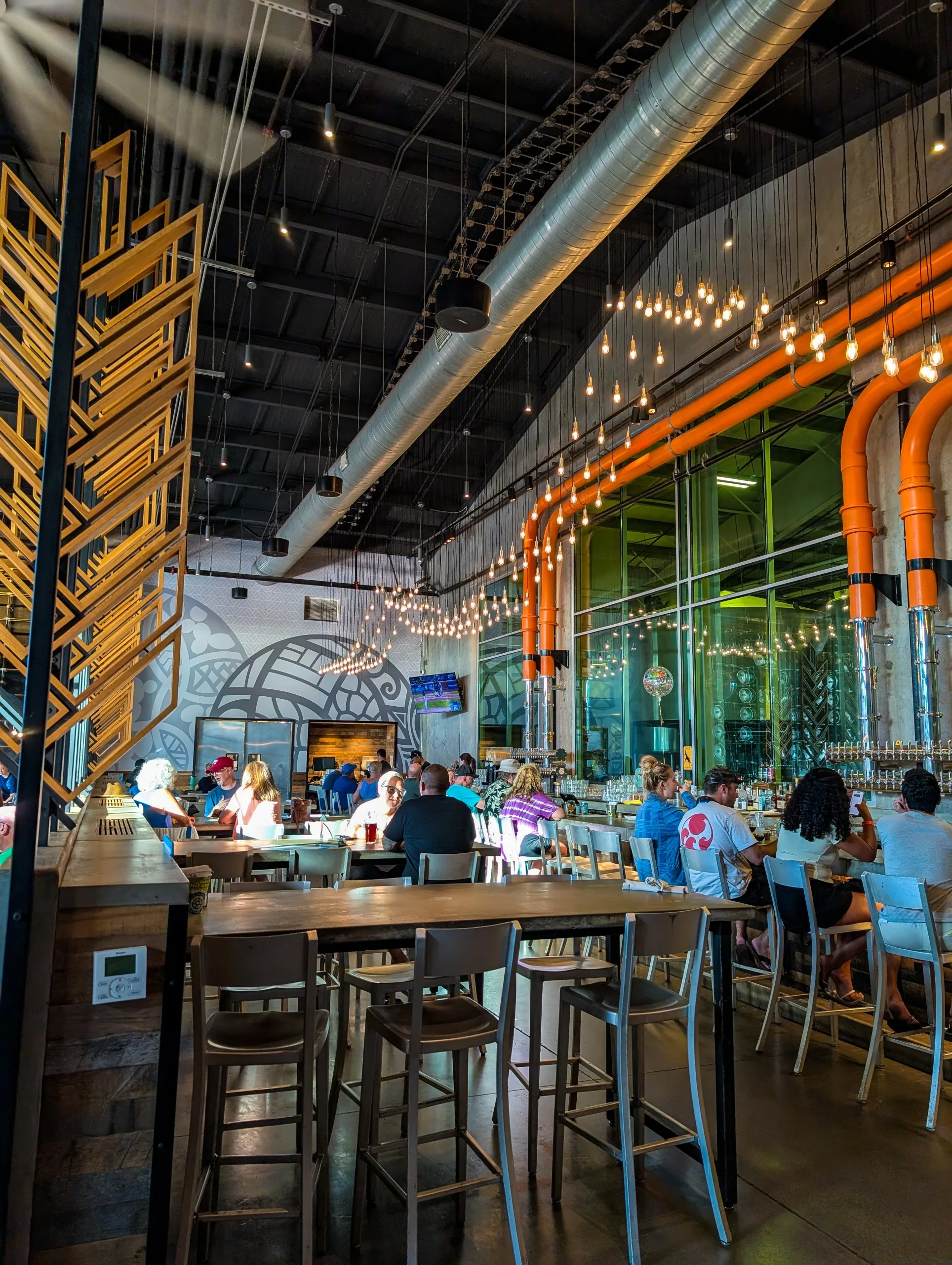 Une brasserie moderne avec de hauts plafonds, des tuyaux apparents et des ampoules Edison