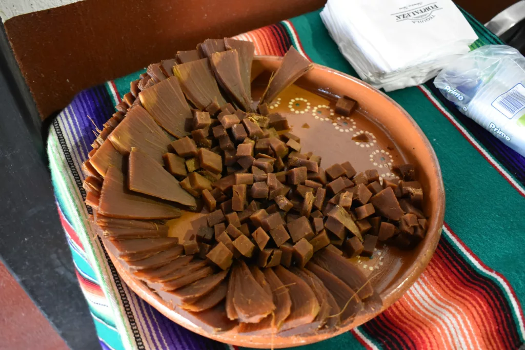 Une assiette ronde en terre cuite remplie de tranches rectangulaires et morceaux d'agave cuits