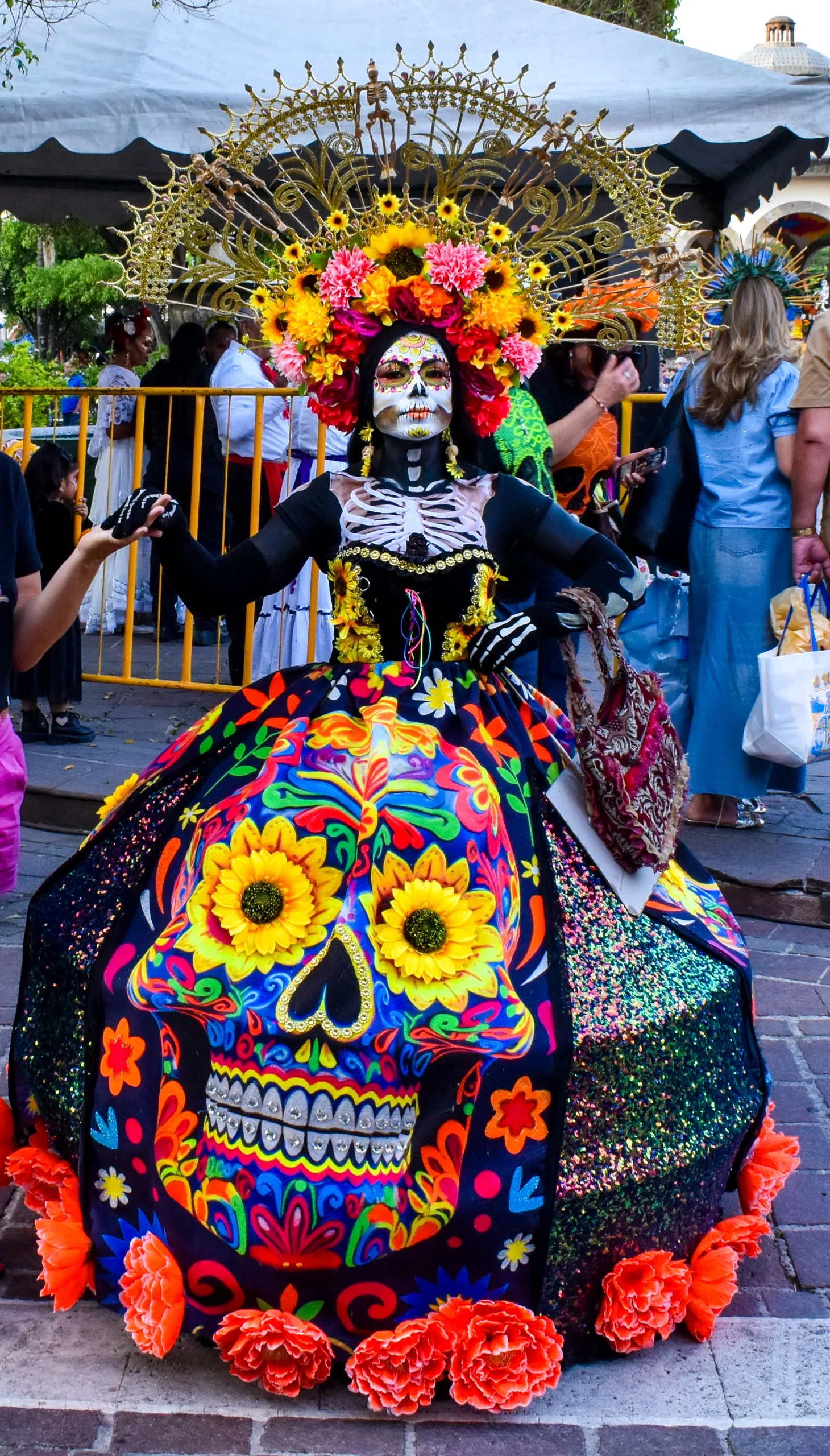 Une femme portant un costume du Jour des morts coloré, maquillée en squelette, ornées de fleurs vives et d'une coiffe décorative pose pour la fête des morts au Mexique.