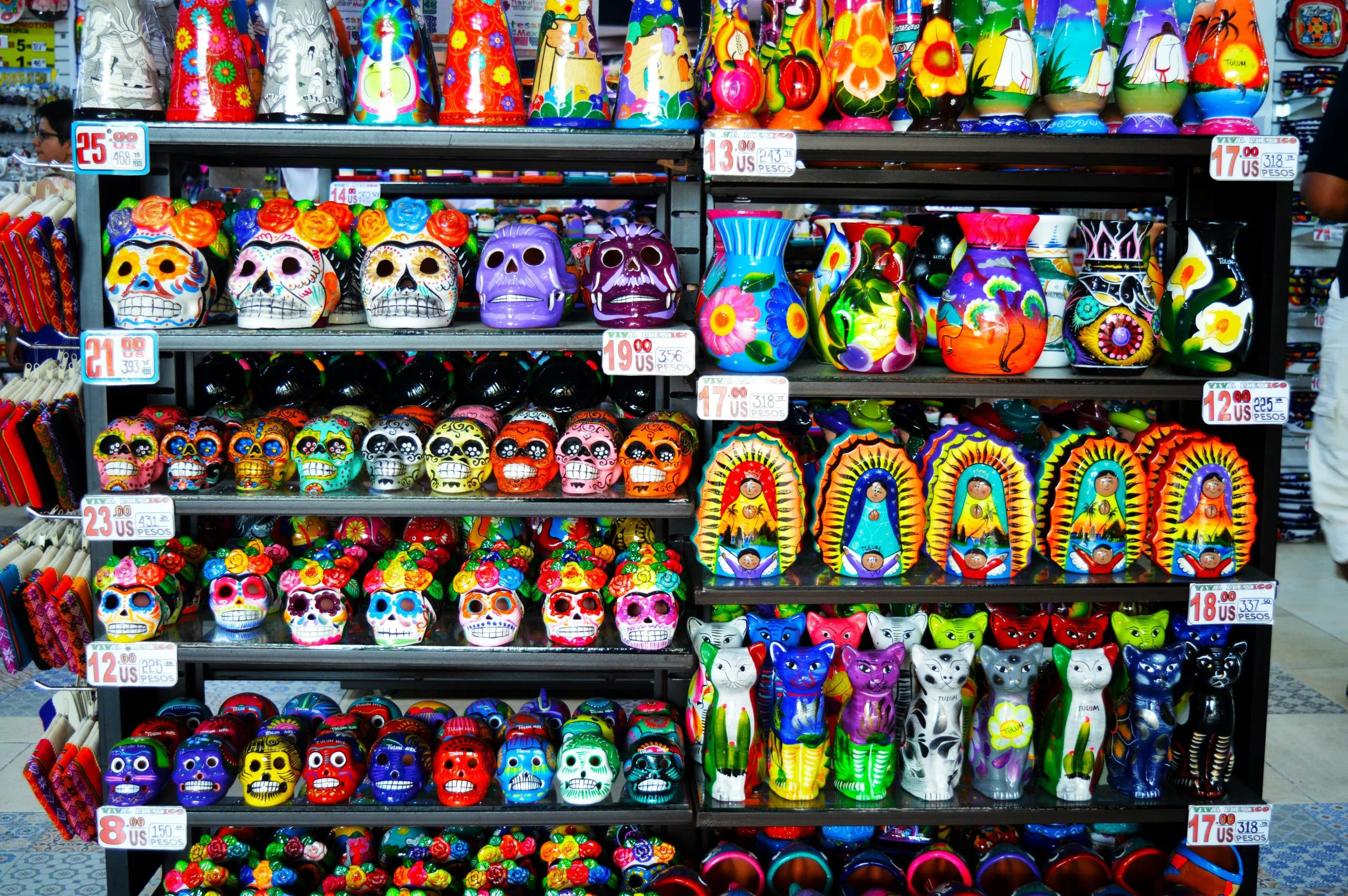 Des étagères présentent des figurines colorées en céramique mexicaine, notamment des calaveras, crânes inspirés de la fête des morts mexicaine