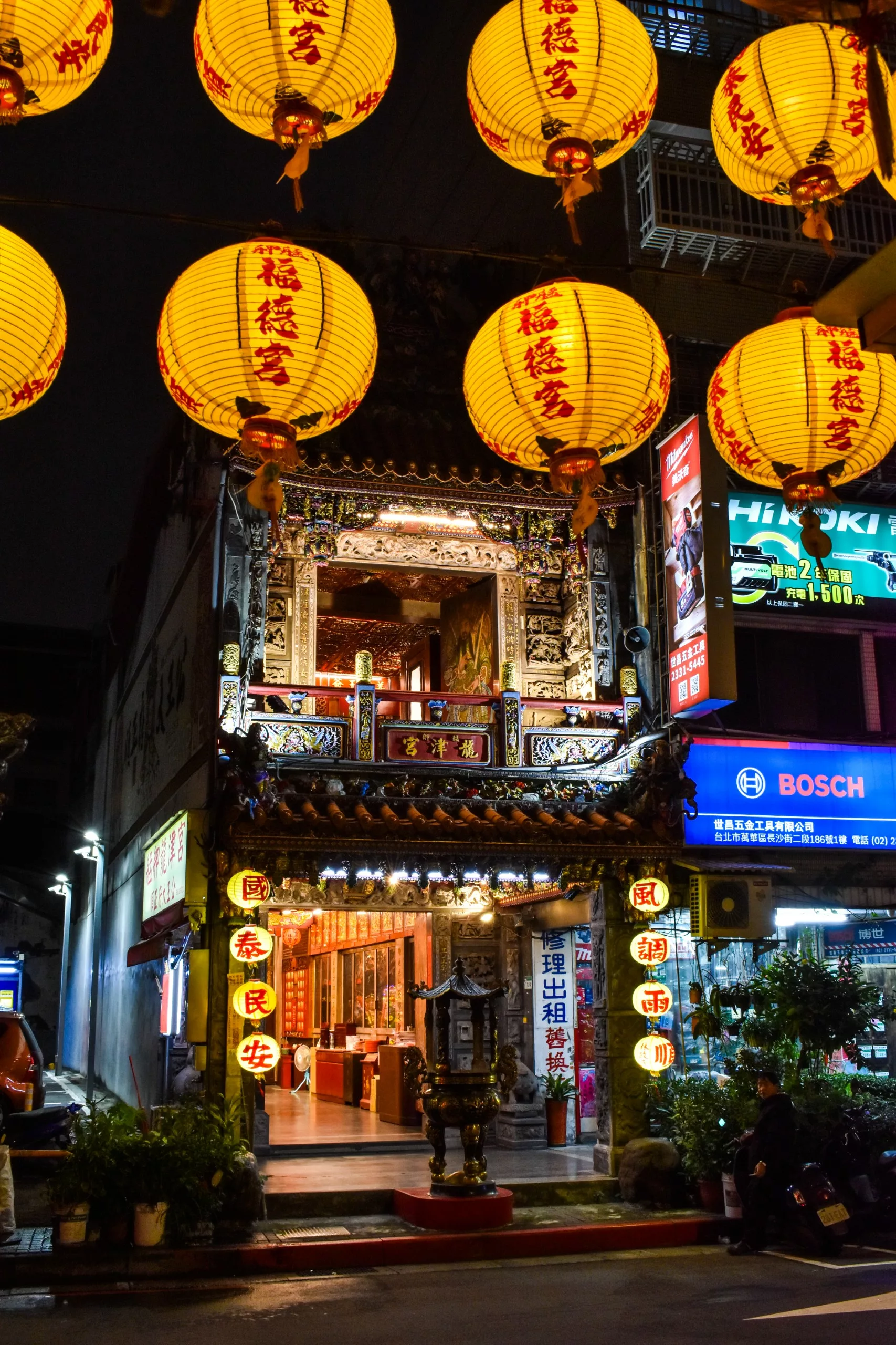 Un temple chinois traditionnel décoré de sculptures ornées et de lanternes allumées la nuit