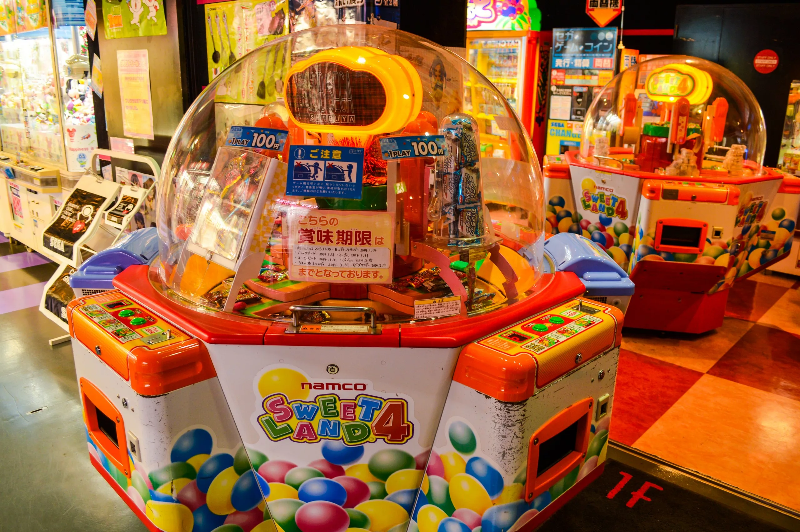Une machine d'arcade Namco Sweet Land 4 aux couleurs vives, avec un dôme transparent, des leviers et des boutons