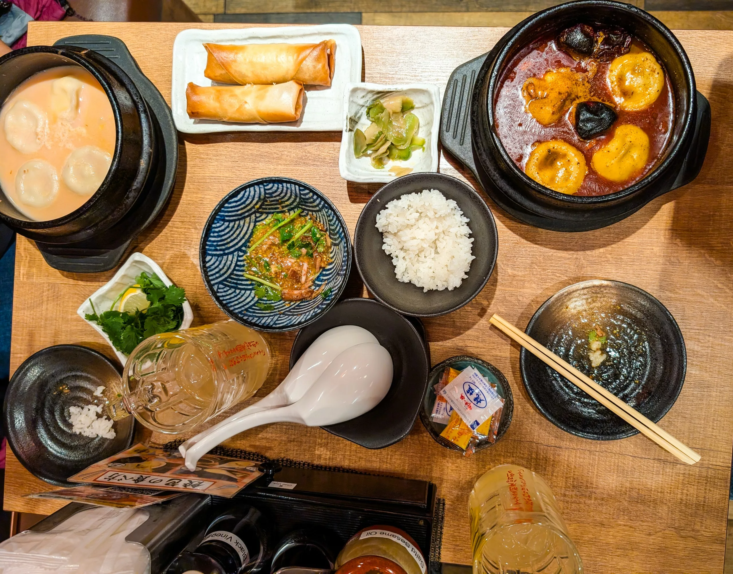 Une table avec une variété de plats asiatiques, notamment des dumplings dans la soupe, des rouleaux de printemps, du curry avec des œufs et des champignons - parfait pour tous ceux qui explorent que faire à Tokyo et qui ont envie d'une expérience culinaire authentique.