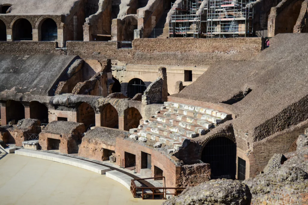 Vue des ruines intérieures du Colisée de Rome, l'un des incontournables à visiter, montrant des sièges en pierre ancienne, des arcs en brique