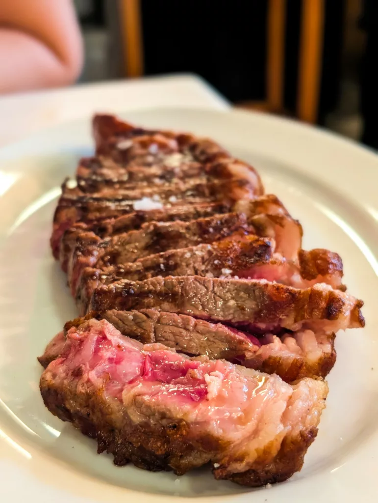 Gros plan d'un steak tranché à point sur une assiette blanche, présentant un extérieur brun saisi et une marbrure rose