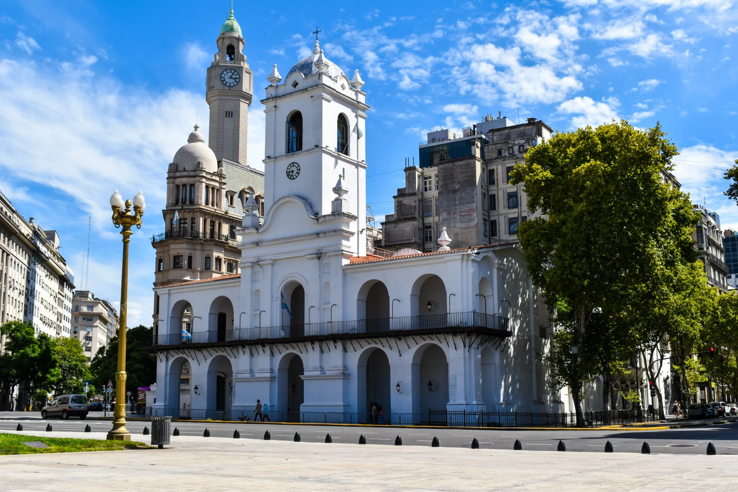 Un bâtiment blanc de style colonial avec des arches et une tour d'horloge centrale se dresse dans une rue de Buenos Aires.