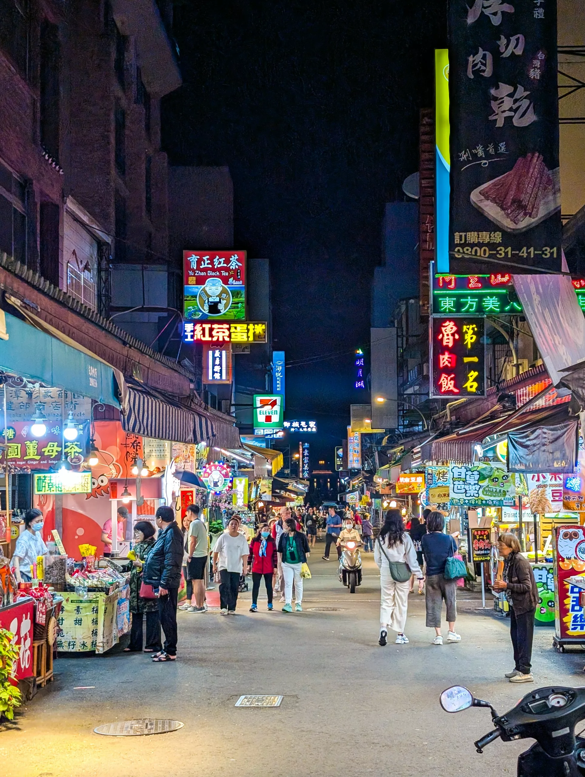 Un marché de nuit animé, avec des gens qui se promènent parmi les étals éclairés et les enseignes colorées écrites en caractères chinois.