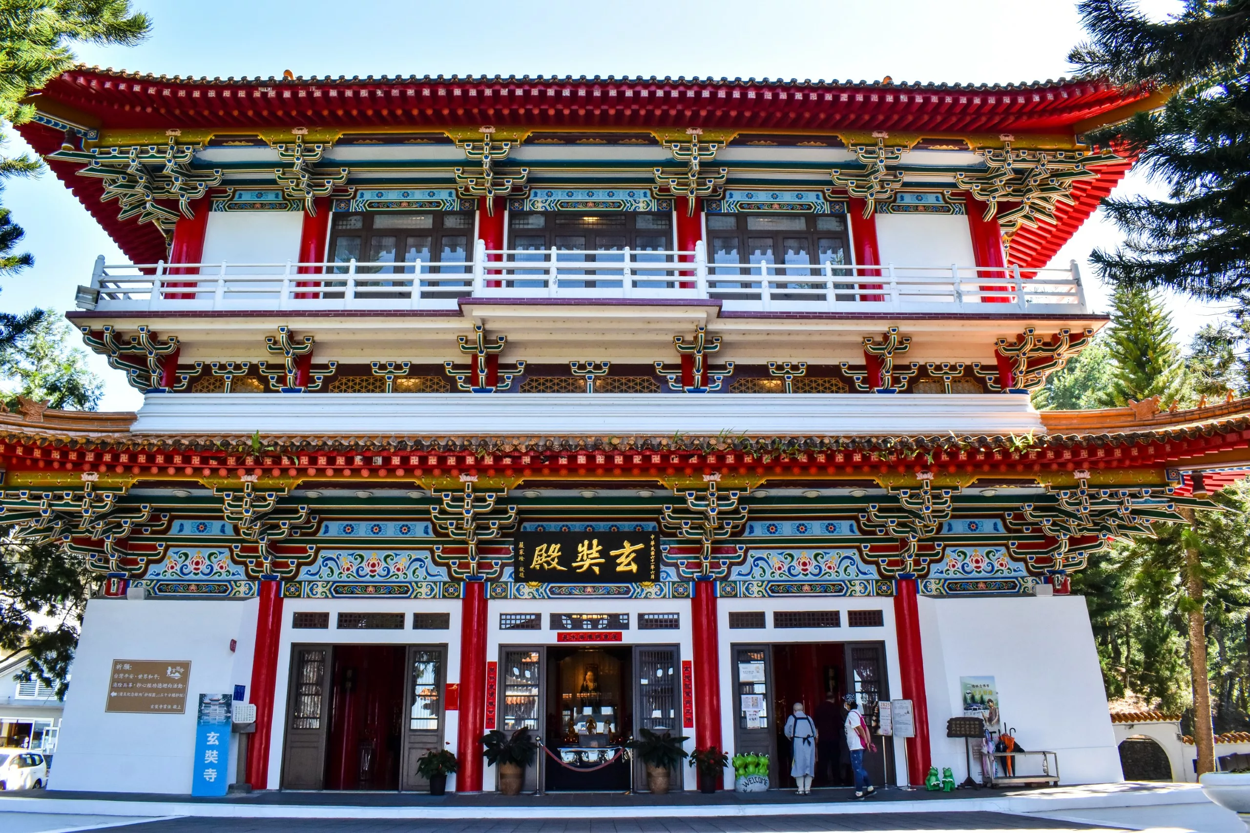 Un temple chinois traditionnel de deux étages, orné de détails rouges, or et verts, de balustrades blanches et d'une large entrée.