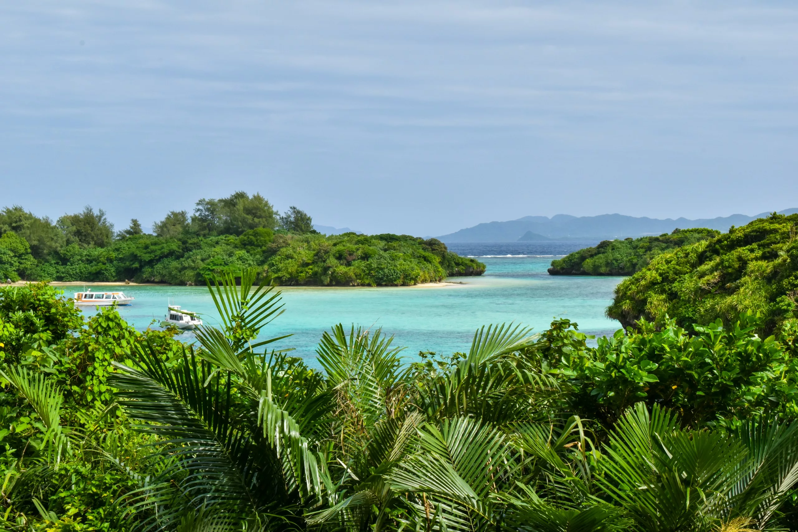 Une baie aux eaux turquoise cristallines, une végétation luxuriante au premier plan et des îles boisées, dans la baie de Kabira, incontournable quand on cherche que faire à Ishigaki