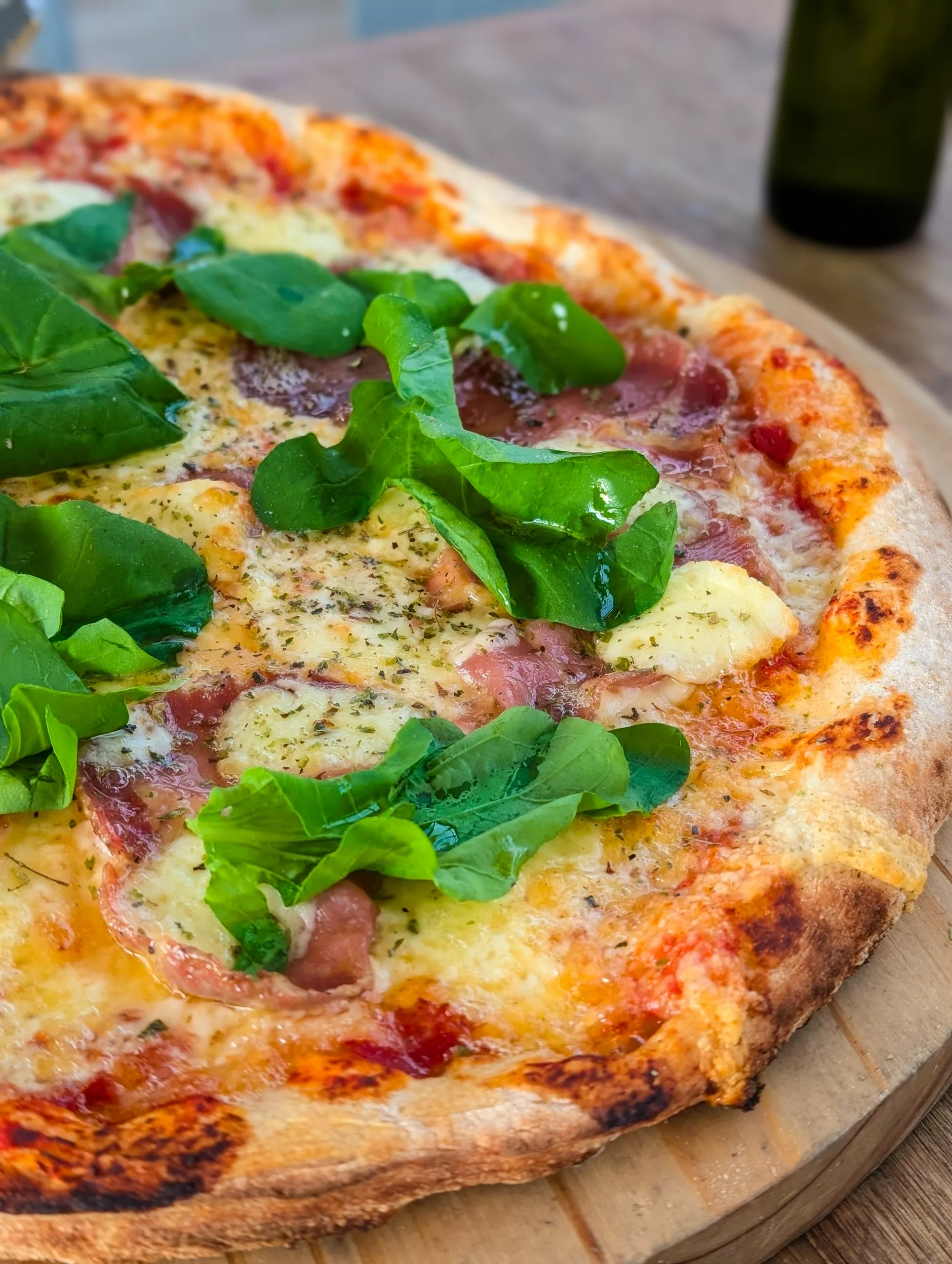 Gros plan sur une pizza avec de la sauce tomate, du fromage et des feuilles de roquette.